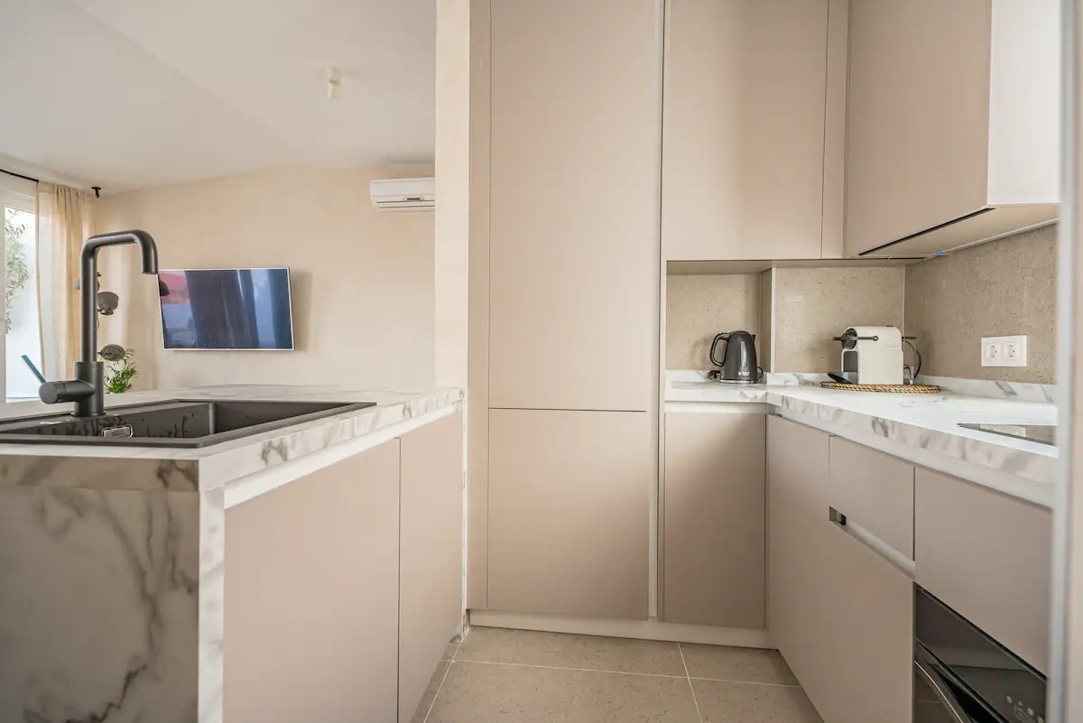 Kitchen with pale cabinets, marble worktop, kettle and coffee machine