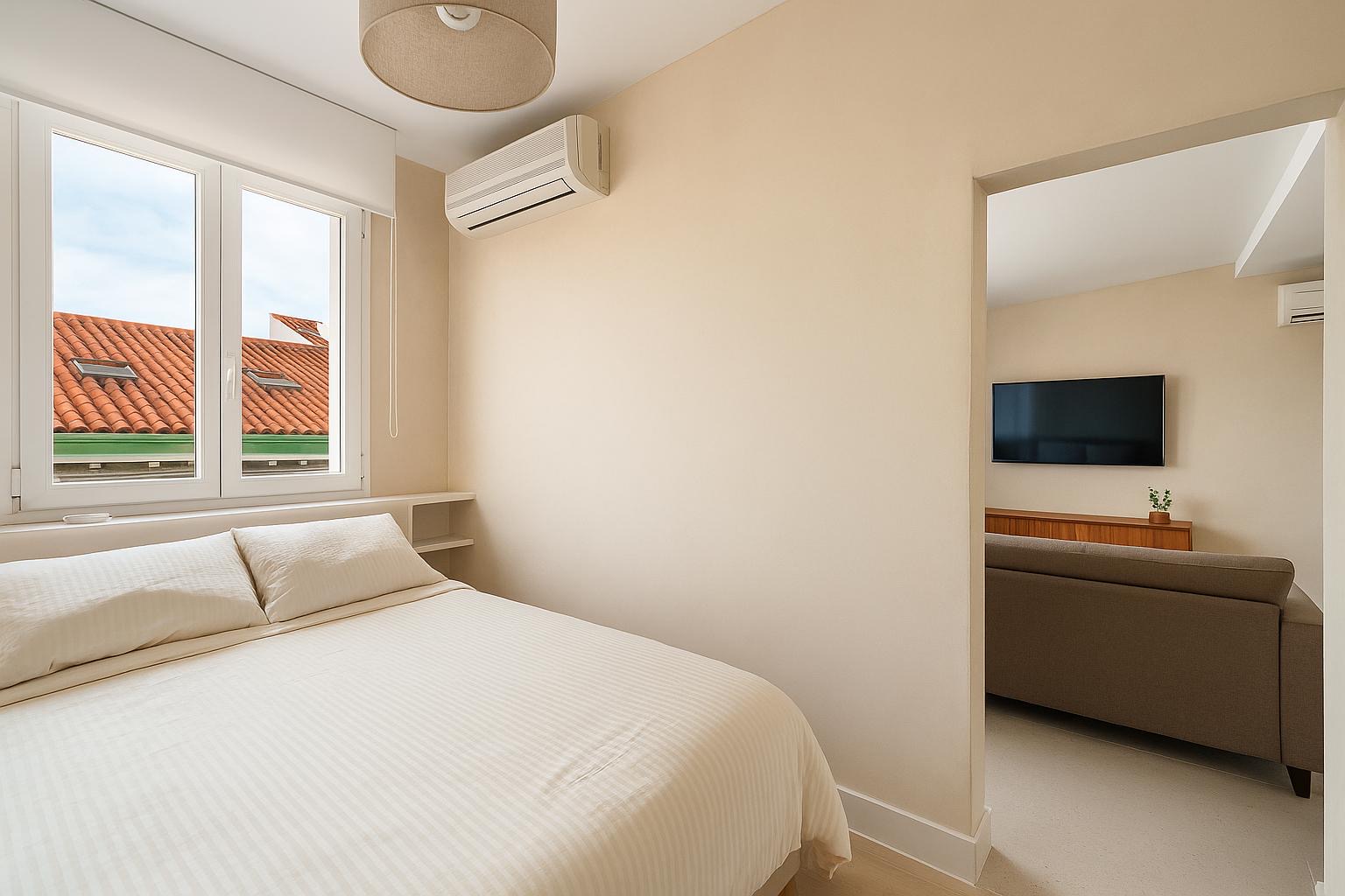 Bright bedroom with a double bed, white linens and a window onto Madrid's tiled rooftops