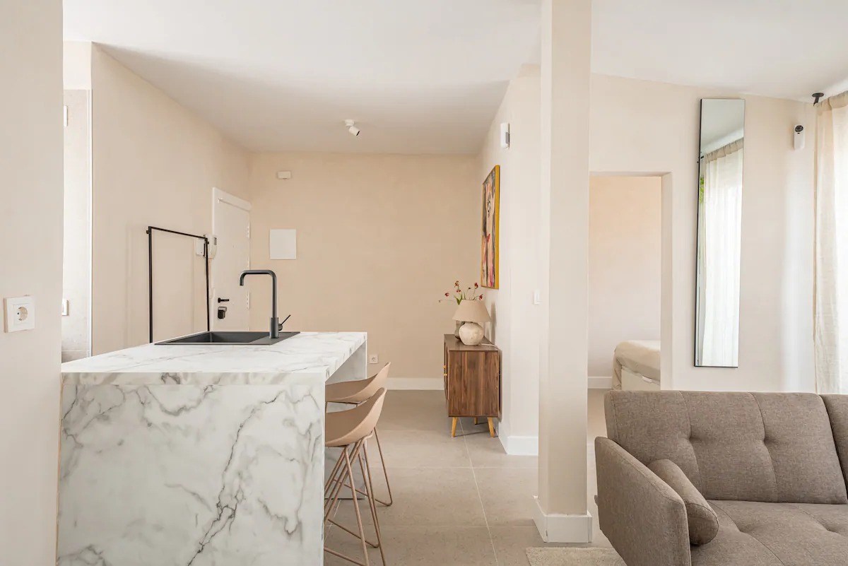 Open-plan kitchen island in white marble beside the living area