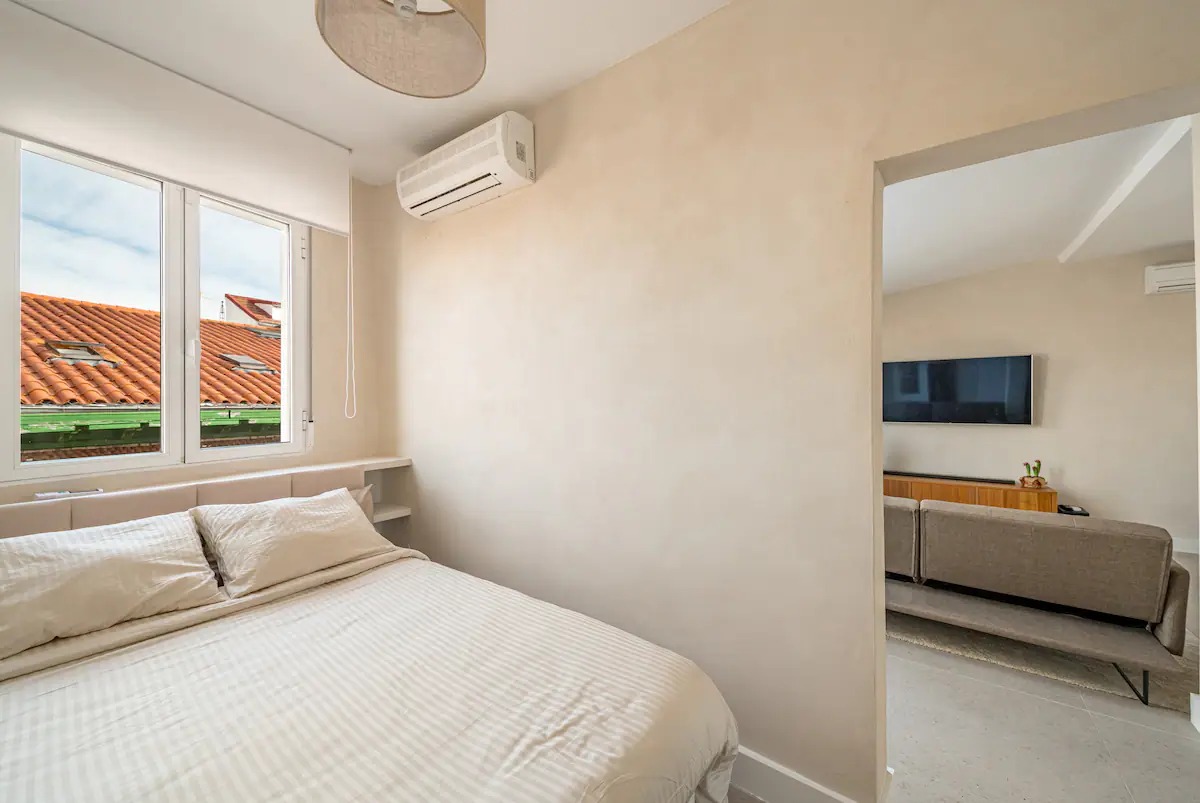 Bright bedroom with a double bed and a window onto the rooftops